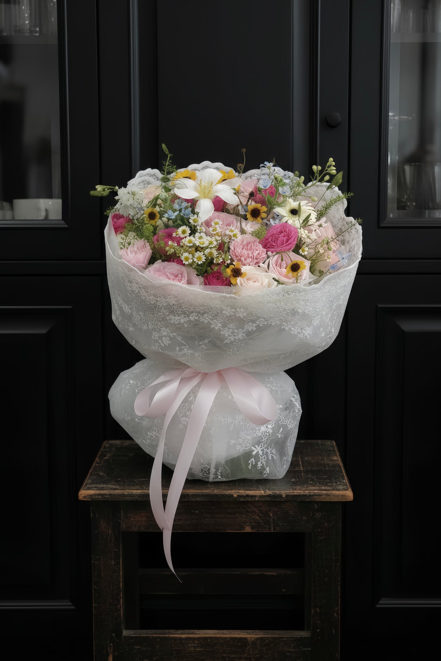 French garden-inspired bouquet with soft pink and lavender spring blooms wrapped in lace and tied with a satin ribbon