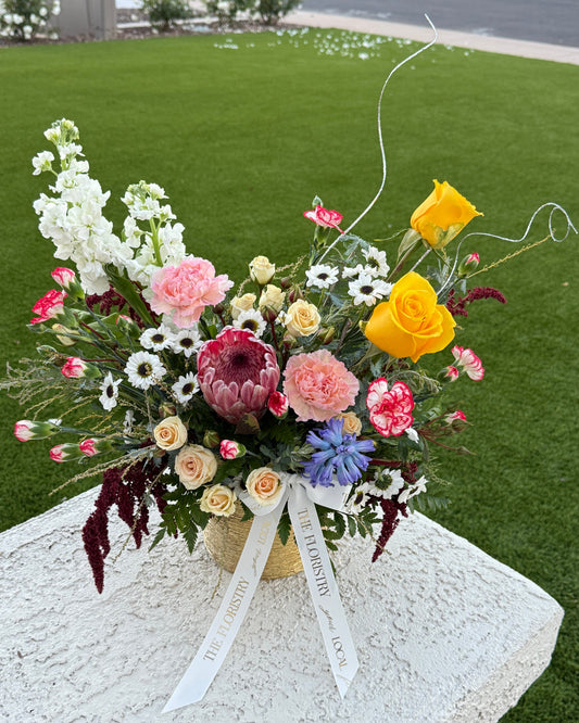 Spring mix floral centerpiece featuring fresh seasonal blooms in soft pastel and vibrant spring colors arranged in a low profile design.