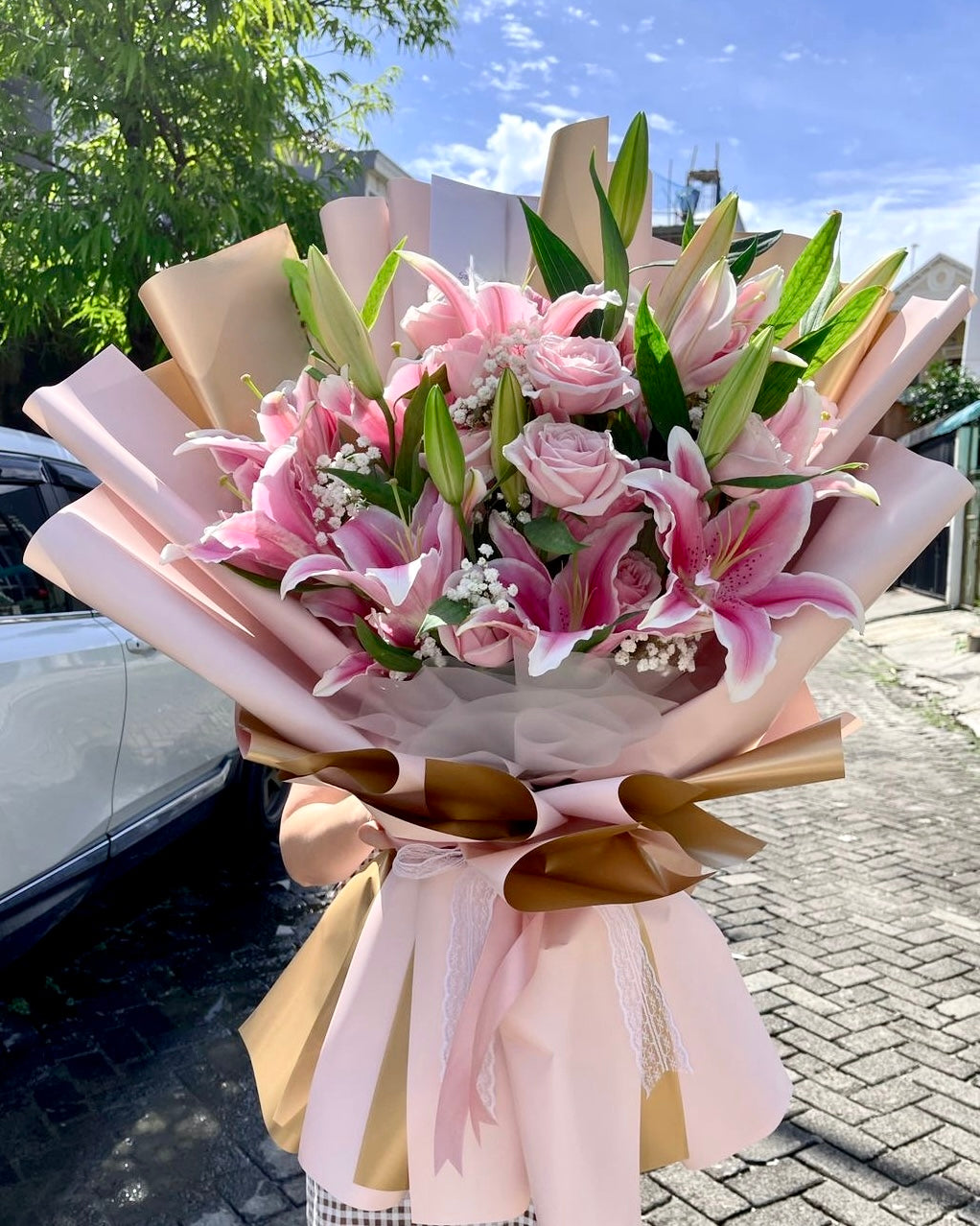 Bouquet of pink flowers with green leaves on a street background