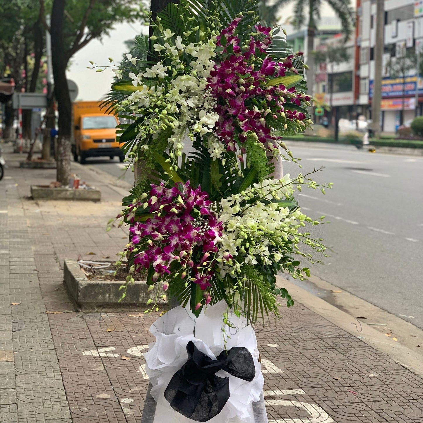 Premium orchid condolence flower stand designed with cascading purple blooms for memorial and funeral services.