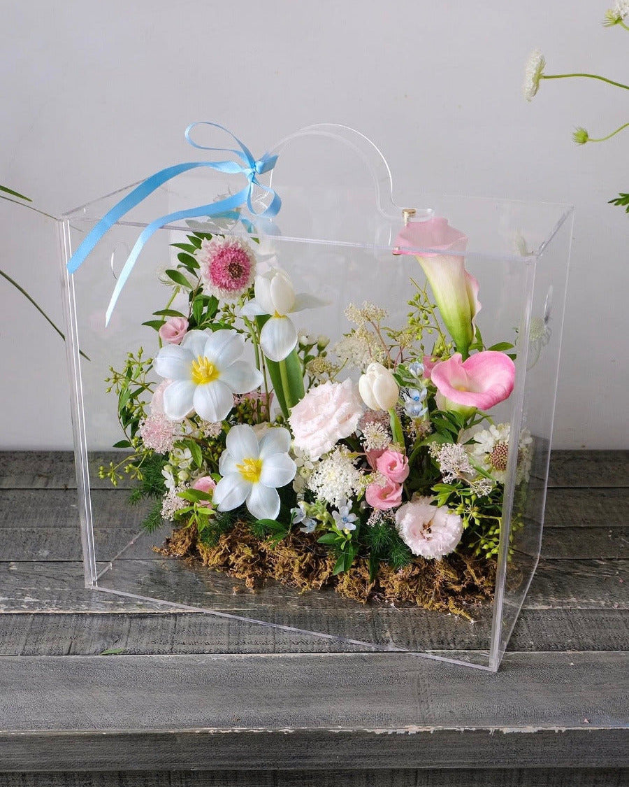 Luxury clear gift boxes featuring modern floral arrangements on a concrete background, perfect for celebration and special occasions.