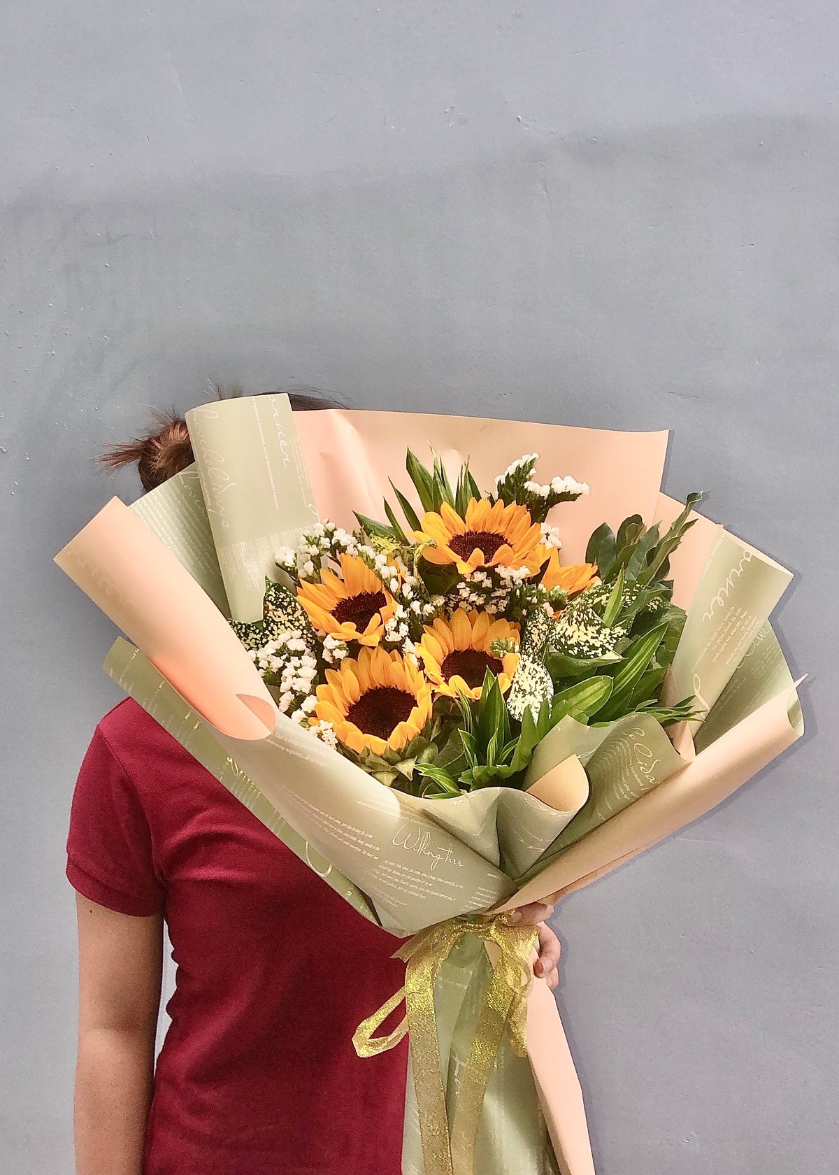 A bouquet of sunflowers wrapped in beige and green paper with a ribbon. Same day flower delivery in Chanler, Arizona