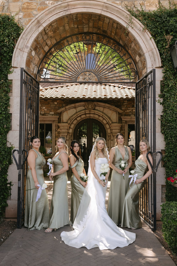 A bride in a white wedding gown with elegant white bridal bouquet and bridesmaids holding bridesmaid bouquets