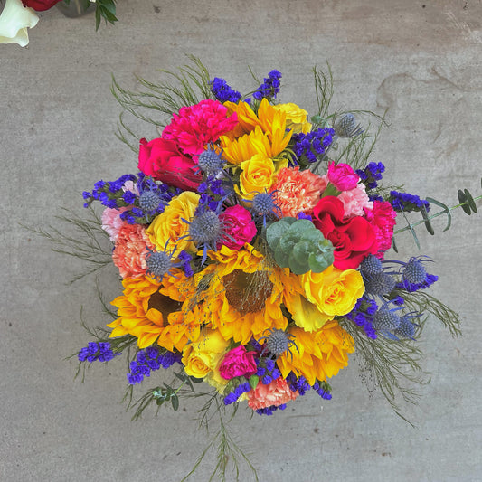 A colorful bouquet of flowers arranged in a vase, featuring shades of pink, yellow, purple, and green.