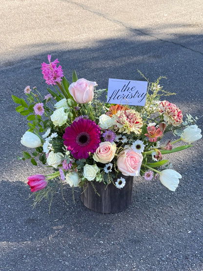 Fresh spring flower centerpiece with mixed blooms, layered textures, and cheerful seasonal tones perfect for a dining table.