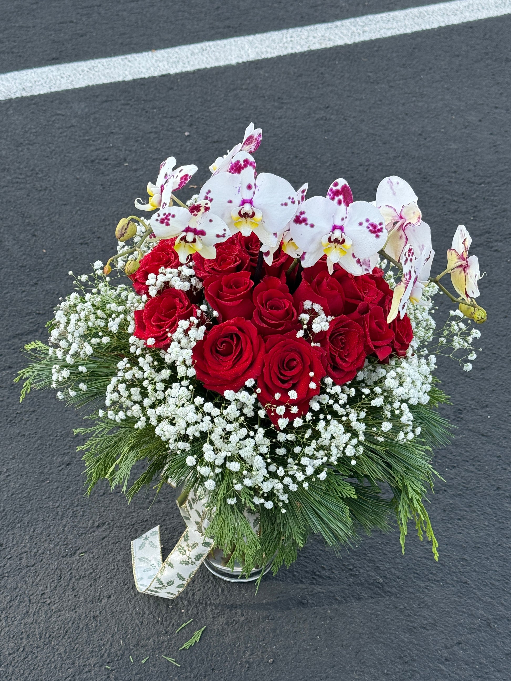 Bouquet of red roses, white orchids, and greenery on a dark background