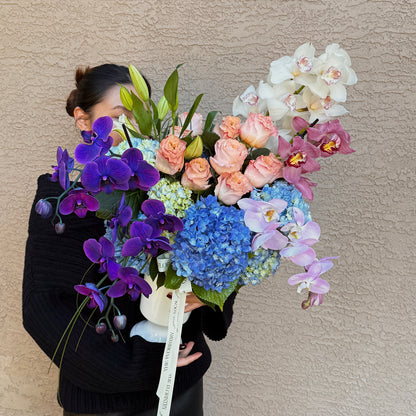 Person holding a large bouquet of colorful flowers against a plain background