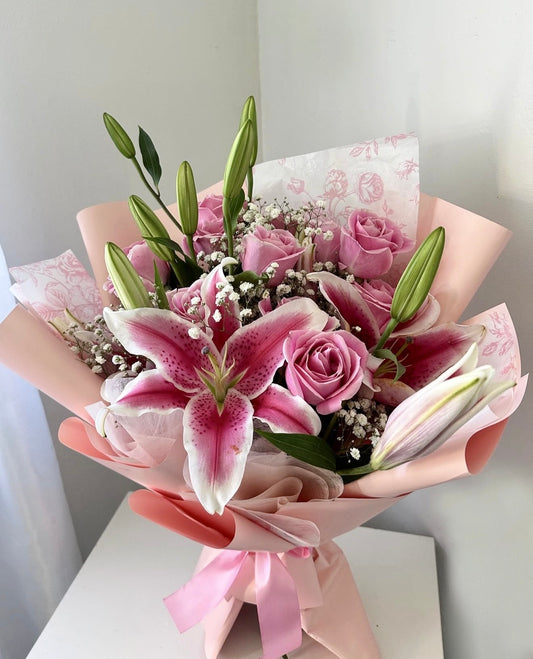 Bouquet of pink flowers with lilies and roses in a pink wrap on a white background