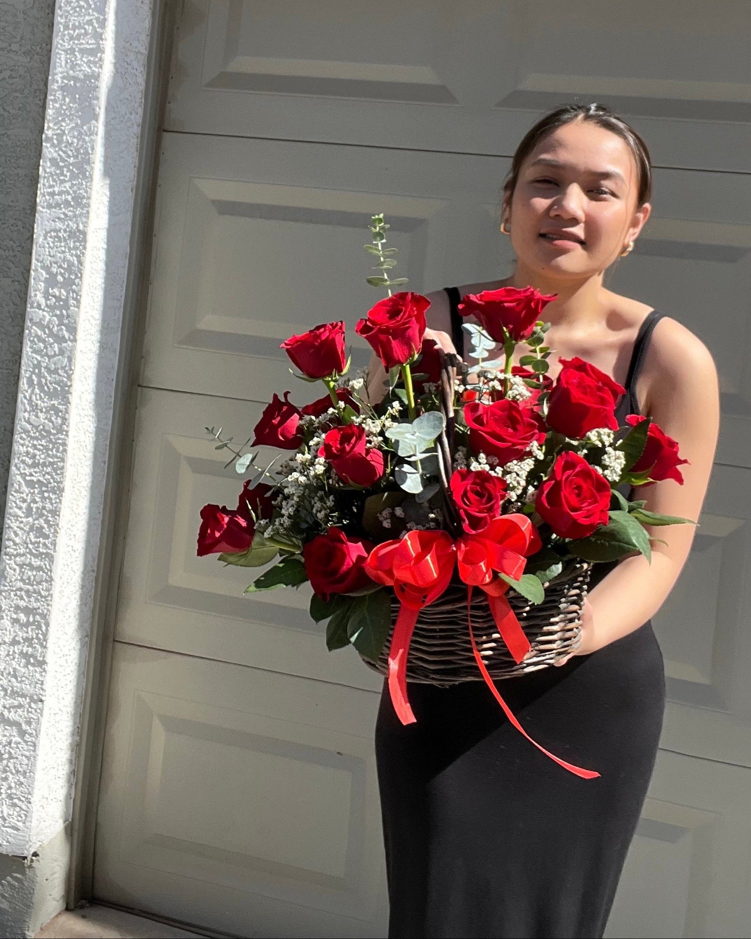 a lady holds a large, beautiful basket featuring premium red roses.