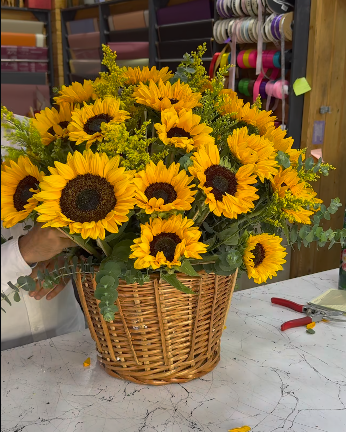 Basket of sunflowers on a marble countertop with a store interior in the background