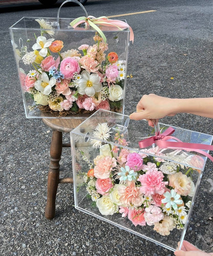 Transparent boxes with floral arrangements on a concrete surface