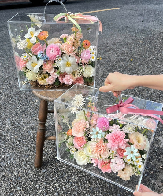 Transparent boxes with floral arrangements on a concrete surface