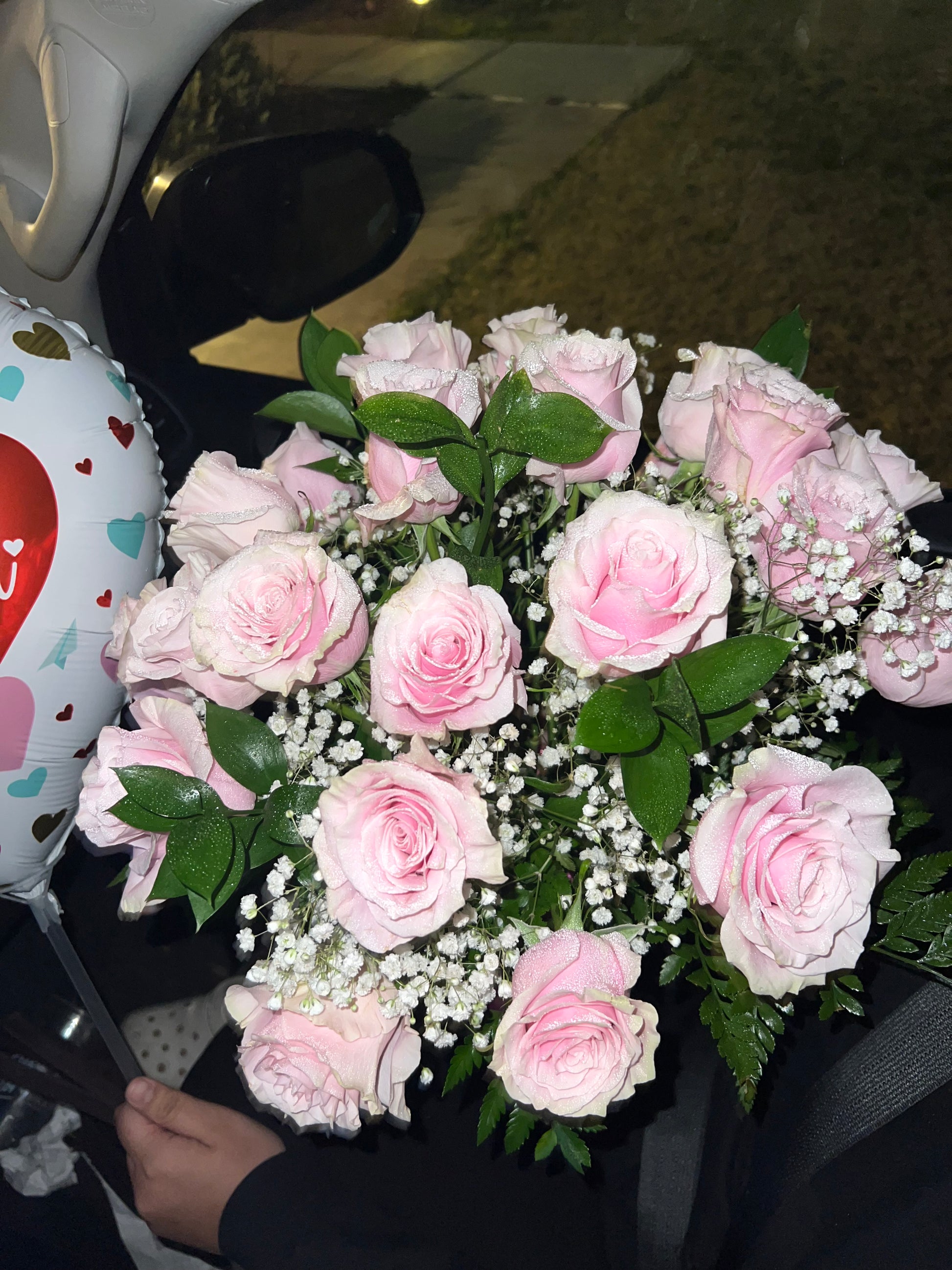 A bouquet of pink and green roses with baby's breath, arranged in a vase.