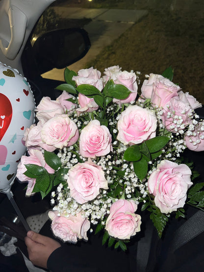 A bouquet of pink and green roses with baby's breath, arranged in a vase.