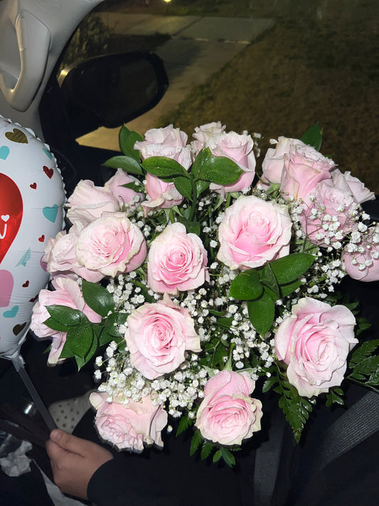 A bouquet of pink and green roses with baby's breath, arranged in a vase.