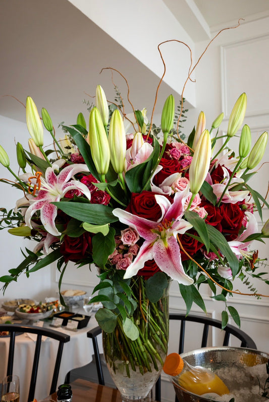 Bouquet of flowers with red roses and white lilies in a vase on a table for delivery in Queen Creek, AZ