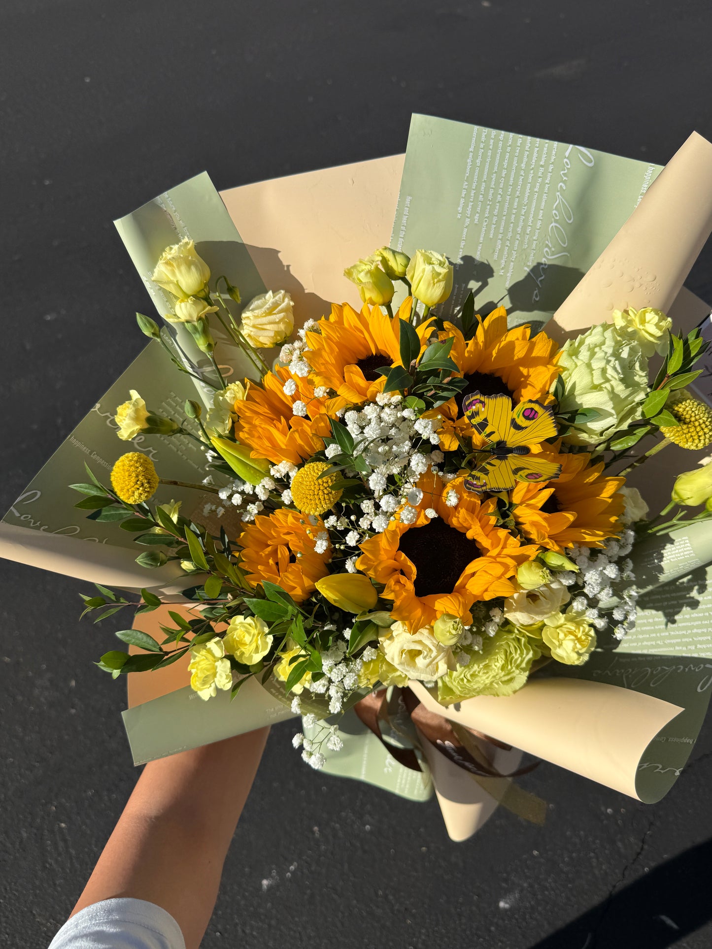 A bouquet of sunflowers wrapped in beige and green paper with a ribbon. Same day flower delivery in Phoenix, Arizona
