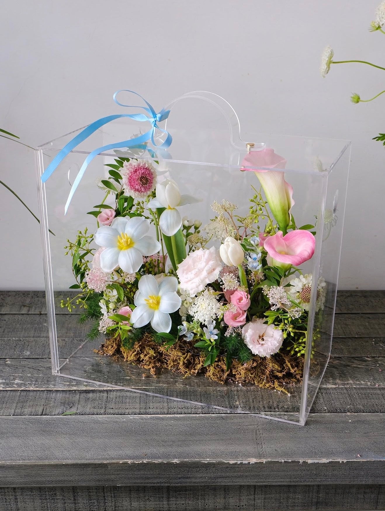 Luxury clear gift boxes featuring modern floral arrangements on a concrete background, perfect for celebration and special occasions.