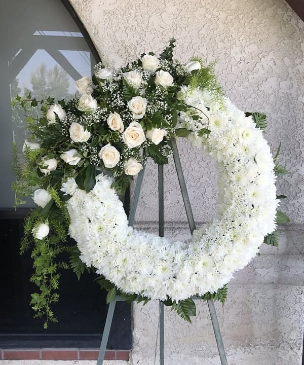 A floral wreath arrangement with white and green flowers, possibly for a funeral or sympathy purpose.