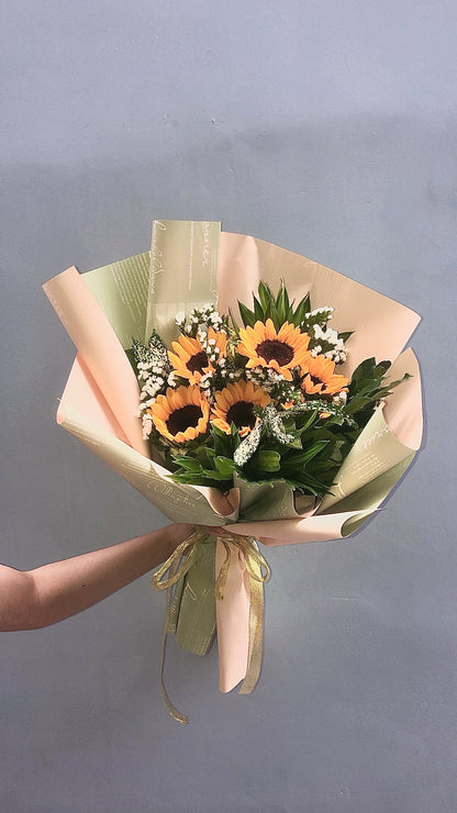 A bouquet of sunflowers wrapped in beige and green paper with a ribbon. Same day flower delivery in gilbert, Arizona
